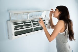 Young Woman Checking Air Conditioner In House